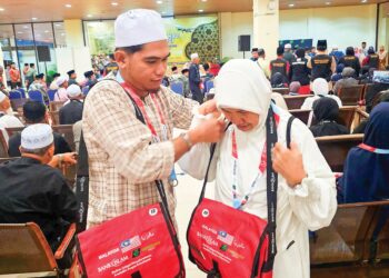 SITI Hawa Ibrahim dibantu anaknya, Sazli Hafizan Zahid membuat persiapan menunaikan haji di Lapangan Terbang Antarabangsa Sultan Mahmud, Kuala Terengganu semalam. – UTUSAN/ZAID MOHD. NOOR