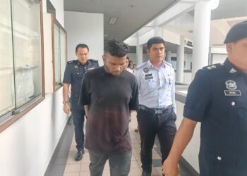 T. KERUBAHKARAN diiringi anggota polis ketika keluar dari kamar mahkamah Majistret, Ayer Keroh hari ini selepas menghadapi enam pertuduhan termasuk memandu secara melawan arus dan mencuri kabel. - UTUSAN/AMRAN ALI