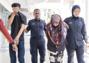 KEDUA-dua tertuduh diiringi anggota polis ketika dihadapkan ke Mahkamah Sesyen Alor Gajah, Melaka hari ini atas pertuduhan mengabaikan bayi lelaki mereka berusia dua bulan. - UTUSAN/MUHAMMAD SHAHIZAM TAZALI