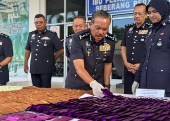 HAMZAH Ahmad (tengah) meneliti peket berisi MDMA di IPD Seberang Perai Tengah, Bukit Mertajam, Pulau Pinang.-UTUSAN/SITI NUR MAS ERAH AMRAN