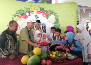 MUHAMAD Fadlee Hassan (kiri) mengiringi  Mohd. Unit A. Bakar mengagihkan buah-buahan tempatan kepada murid sewaktu Kempen Lebihkan Makan Buah-buahan dan Sayur-sayuran Tempatan Peringkat Negeri Terengganu di Sekolah Kebangsaan Seri Berang, Hulu Terengganu. - UTUSAN/ NOOR HAYATI MAMAT