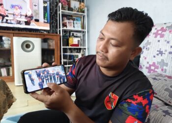 KOPERAL Nizam Tarmizi menunjukkan gambar kenangan rakan-rakannya ketika ditugaskan membuat kawalan di Teluk Intan Selasa lalu. - UTUSAN