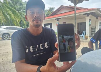 MOHD. FADZLI Kadar menunjukkan gambar terakhir arwah anaknya (bertopi keledar) yang maut dalam kemalangan itu. - UTUSAN/ ISKANDAR SHAH MOHAMED
