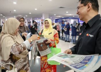 Pengurus Pengedaran Media Mulia Sdn. Bhd., Mohammad Fahmi Asraf Khan (kanan) mengedarkan akhbar Utusan Malaysia dan Kosmo! kepada orang ramai secara percuma pada Pesta Buku Antarabangsa Kuala Lumpur 2025 (PBAKL 2025) di Pusat Dagangan Dunia Kuala Lumpur (WTC KL) semalam. – Utusan/FARIZ RUSADIO
