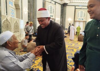 SYED Muhammad Hazwan Syed Azmai  menyantuni jemaah Masjid Ubudiah Kuala Kangsar selepas selesai solat Jumaat di Kuala Kangsar, Perak, semalam. - UTUSAN/FADZIL ZAINOL