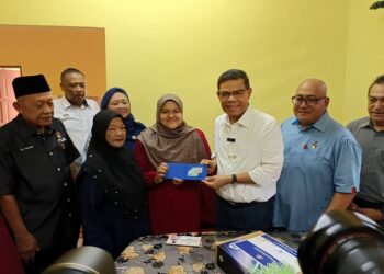 SAIFUDDIN Nasution Ismail menyampaikan MyKad kepada Nurul Arini pada Program Ziarah dan Meraikan Pelajar Cemerlang SPM di Kampung Bukit Tembok, Pasir Panjang, di sini, hari ini. UTUSAN/NOR AINNA HAMZAH
