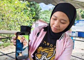 ROHAIZA Mazlan menunjukkan gambar kenangannya bersama bapa, Mazlan Ahmad yang maut dilanggar lori ketika bermotosikal untuk pulang dari masjid di Jalan Ipoh–Kuala Lumpur, Kampar semalam.  - UTUSAN