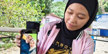 ROHAIZA Mazlan menunjukkan gambar kenangannya bersama bapa, Mazlan Ahmad yang maut dilanggar lori ketika bermotosikal untuk pulang dari masjid di Jalan Ipoh–Kuala Lumpur, Kampar semalam.  - UTUSAN