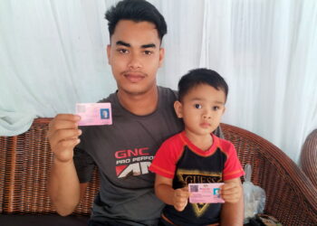 MUHAMMAD Fakrullah Mohd. Ariff bersama Muhammad Fayyad Syahiran Muhammad Fairuz yang menderita penyakit glaukoma menunjukkan kad orang kurang upaya (OKU) ketika ditemui di Kampung Balik Bukit, Setiu, Terengganu. – UTUSAN / WAN ZURATIKAH IFFAH WAN ZULKIFLI