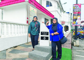 FAIRUS Mohd. (kanan) bersama rakannya mengambil kesempatan bergambar di Batu 0 KM di Bandar Kuala Lipis di Lipis, Pahang.