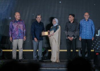 JOHARI Abdul Ghani menyampaikan Anugerah Jubli Perak Lembaga Minyak Sawit Malaysia (MPOB) kepada Penolong Pengarang Ekonomi Utusan Malaysia, NURFARAHIN HUSSIN sempena Malam Gala Jubli Perak MPOB di Marriot Hotel Putrajaya di sini, malam ini. - UTUSAN/FAIZ ALIF ZUBIR