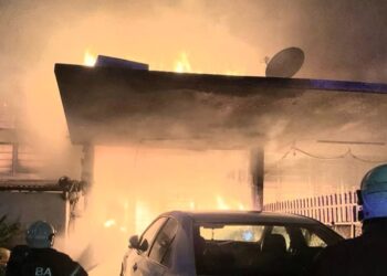 DUA anggota bomba dilihat bertungkus-lumus memadam kebakaran melibatkan tiga unit rumah teres setingkat di Taman Island Glades, Gelugor, George Town, Pulau Pinang malam tadi.-GAMBAR/JBPM PULAU PINANG