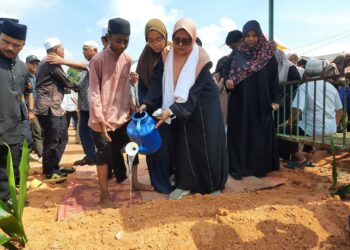 ROZAIDAH Ahmad menyiram air mawar di pusara anaknya Akmal Wafi Annuar yang disemadikan di Tanah Perkuburan Islam Masjid Tunku Abdul Rahman Putra, Kampung Sungai Limau, Lunas di Kulim.