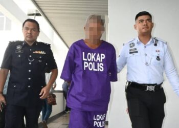 PEMANDU lori pembancuh simen berusia 49 tahun diiringi anggota polis selepas dibawa ke Mahkamah Majistret, Ayer Keroh, Melaka untuk permohonan reman. - UTUSAN/AMRAN ALI