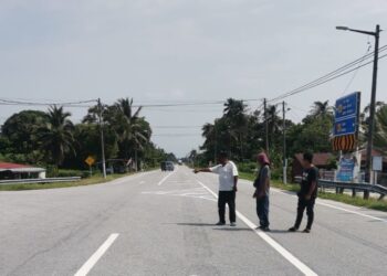 PENDUDUK menunjukkan simpang tiga ke arah Chuicak dan Pekan Langkap berdekatan lokasi kemalangan trak FRU di Teluk Intan, Perak, minggu lalu.-UTUSAN/AIN SAFRE BIDIN.