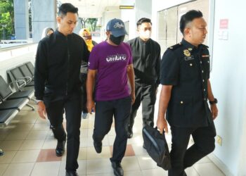ROSDI Pilus (tengah) dibawa ke Mahkamah Sesyen Seremban hari ini bagi didakwa atas dua pertuduhan menggunakan kedudukannya bagi mendapatkan kontrak untuk syarikat isterinya pada tahun 2021 dan 2022.-UTUSAN/MOHD. SHAHJEHAN MAAMIN