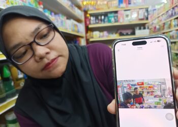 NURASYIKIN Ishak menunjukkan gambar lelaki yang terakam dalam CCTV yang melarikan sebanyak 15 kampit beras dan satu pukal gula dalam kejadian di Rembau Central, Rembau, semalam. UTUSAN/NOR AINNA HAMZAH