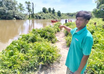 MOHAMMAD Noor Amirul menunjukkan lokasi mangsa tergelincir semasa memancing di Sungai Pengkalan Nangka di Kampung Kok Kebit, Tumpat, Kelantan. - UTUSAN/ROHANA ISMAIL