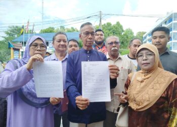 MOHD. Razli Ahmad (tengah) menunjukkan laporan polis yang dibuatnya di Lenggong, Perak. - UTUSAN/FADZIL ZAINOL