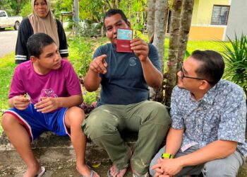 MOHD. Zulkifly Mustafa (dua dari kanan) menunjukkan MyKad anaknya yang diserahkan oleh Mohd. Azmawi Fikri (kanan) di Taman Agropolitan Rantau Manis, Gua Musang, Kelantan. – UTUSAN/AIMUNI TUAN LAH
