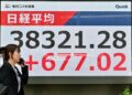 Seorang pejalan kaki berjalan melepasi papan elektronik yang menunjukkan harga saham semasa dagangan pagi di Bursa Saham Tokyo pada Selasa 13 Mei. - AFP