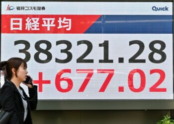 Seorang pejalan kaki berjalan melepasi papan elektronik yang menunjukkan harga saham semasa dagangan pagi di Bursa Saham Tokyo pada Selasa 13 Mei. - AFP