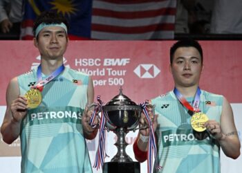 Aaron Chia dan Soh Wooi Yik bersama hadiah kemenangan  menjuarai Kejohanan Badminton Terbuka Thailand di Bangkok, semalam. - AFP