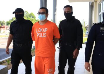 ASROLFANDI Ab. Suki (tengah) diiringi anggota polis semasa menghadiri prosing perbicaraan di Mahkmah Sesyen Pasir Mas, Kelantan. - UTUSAN/KAMARUL BISMI KAMARUZAMAN