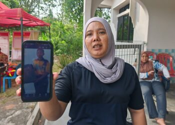 SITI Norehan Azhar menunjukkan gambar Muhamad Aidil Asyraf Fadli yang hilang ketika keluar mencari lembu di Kampung Permatang Pasir, Melaka. - UTUSAN/AMRAN ALI