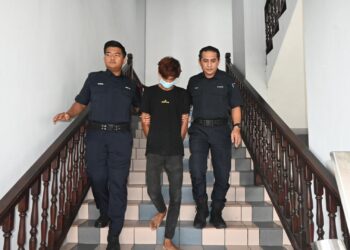 AHMAD Dzul Fiqar Ahmad Fardzil diiringi anggota polis keluar dari Mahkamah Sesyen, Ayer Keroh, Melaka selepas menghadapi lima pertuduhan berkaitan amang seksual fizikal. - UTUSAN/AMRAN ALI