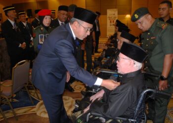 Adly Zahari memakaikan pingat PJM kepada seorang veteran ATM berkerusi roda pada Majlis Penganugerahan Pingat Jasa Malaysia (PJM) di Pusat Dagangan Antarabangsa Melaka (MITC), Ayer Keroh, Melaka. UTUSAN/AMRAN MULUP