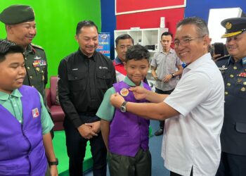 ADLY Zahari memakaikan lencana TV Pusat Sumber Sekolah (TVPSS) kepada seorang murid pada Majlis Peluncuran Program Digitalisasi Sekolah Dalam Kem di SK Sultan Sir Ibrahim, Kluang.