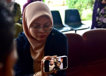 MASTURADIANA Ibrahim menunjukkan gambar Nurul Efendy Ibrahim dan Muhammad Nur Daniel Nurul Efendy ketika ditemui di Hospital Melaka. - UTUSAN/ARIF HAMIZAN MISKON