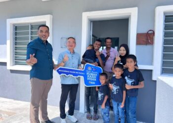 KHOO Poay Tiong menyerahkan kunci Rumah Kasih Ihsan kepada Muhammad Razmi (tengah) sekeluarga sambil disaksikan Mohd. Noor Helmy di Kampung Padang Semabok, Melaka. – UTUSAN/AMRAN ALI