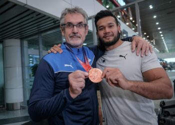 IRFAN (kanan) bersama jurulatihnya menunjukkan pingat gangsa yang dimenangi pada Kejohanan Olahraga Asia (ATC) 2025 ketika tiba di KLIA, kelmarin.