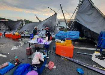 PARA peniaga membersihkan khemah serta baranagan jualan mereka yang rosak dalam kejadian ribut di tapak ekspo sebuah karnival makanan di Kulim, Kedah.-UTUSAN/AZAHAR HASHIM