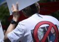SEORANG penunjuk perasaan memakai baju dengan lambang mengecam Donald Trump dan Elon Musk semasa perhimpunan Hari Pekerja di Washington.-AFP