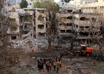 PASUKAN penyelamat berdiri di tengah runtuhan bangunan yang rosak di bandar Tel Aviv, berikutan serangan peluru berpandu Iran semalam.- AFP