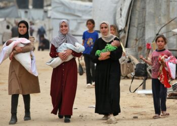 WANITA Palestin berjalan sambil menggendong bayi mereka di kem Jabalia di utara Gaza, pada 8 April lalu.- AFP