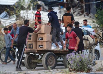 ENDUDUK Palestin mengangkut bekalan makanan dari pusat agihan bantuan GHF di tengah Semenanjung Gaza.-AFP