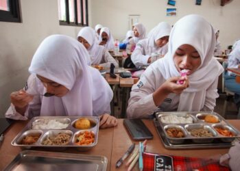 PELAJAR menikmati makan tengah hari pada hari pertama pelaksanaan program makanan percuma di Sekolah Menengah Atas Negeri 11, Jakarta Timur.-AFP