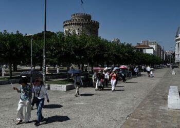 PELANCONG berjalan sambil memegang payung berhampiran Menara Putih ketika gelombang haba melanda Thessaloniki, di Greece.- AFP