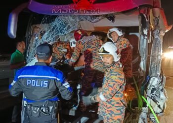 ANGGOTA bomba mengeluarkan penumpang bas yang terlibat kemalangan dengan sebuah lori tunda di lebuh raya PLUS dekat Tapah. - UTUSAN/IHSAN JBPM