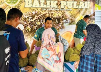 MOHD. Hilmi Che Rose (tengah) melayan pelanggan di gerainya yang dikenali dengan nama YB Durian Balik Pulau di Balik Pulau, Pulau Pinang semalam.