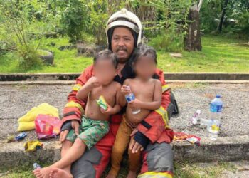 MOHD. Zulkifli Abd. Azis memangku dua beradik yang diselamatkan bersama rakan setugasnya dalam kebakaran di Taman Sri Kota, Kuala Kedah, semalam.