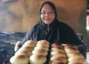 MAZIAH Abd. Rahman menunjukkan roti yang dibakar secara tradisional menggunakan dapur kayu di rumahnya di Kampung Bukit Gemuruh, Hulu Terengganu. - UTUSAN/NOOR HAYATI MAMAT