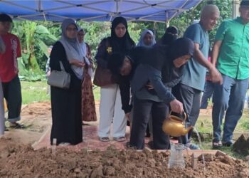 NORMAH Mohd. Yusoff menyiram air di pusara Allahyarham Sheqal di Tanah Perkuburan Islam Kemuning, Kampung Tanjung Putus di Raub, Pahang.