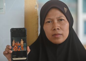 SURIATI Samat menunjukkan gambar Jamal Azizul sekeluarga yang diambil pada Hari Raya Aidiladha yang lalu ketika ditemui di Unit Forensik Hospital Pekan di Pekan, Pahang. - FOTO/SHAIKH AHMAD RAZIF