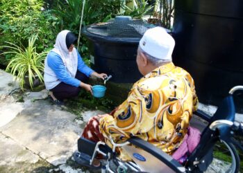 ROHANA Abdul Aziz menadah air dari tangki yang dibeli untuk memandikan suaminya yang lumpuh di Desa KEDA Lahar Tunjung, Pendang, Kedah.
– MINGGUAN/SHAHIR NORODIN