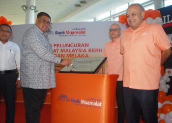 Ab. Rauf Yusoh menandatangani plug sambil diperhatikan Khairul Kamarudin pada perasmian Bank Muamalat Berhad Cawangan Melaka di MIBC, Ayer Keroh, Melaka. UTUSAN/AMRAN MULUP